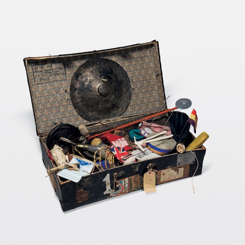 An open suitcase full of assorted objects, including a light bulb, miniature British flag, and cymbal. Part of Alexander Calder's Circus, Whitney Museum of American Art.